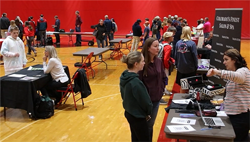 A crowd of people works its way through booths in the EHS gym